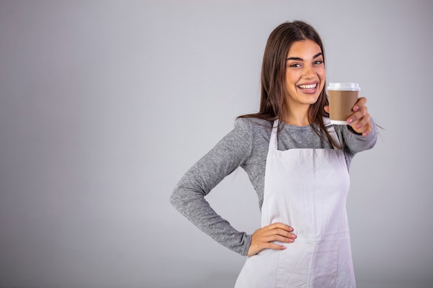 Foto una cameriera che tiene e che serve un bicchiere di carta di caffè caldo su grigio