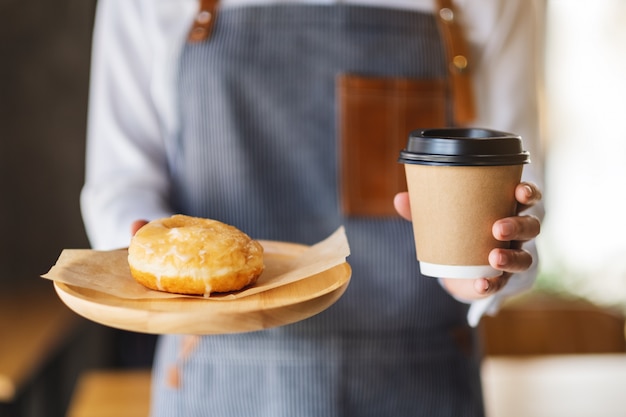 A waitress holding and serving a piece of homemade donut in wooden tray and a paper cup of coffee