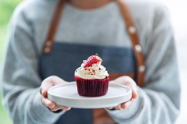 A waitress holding and serving a piece of red velvet cupcake