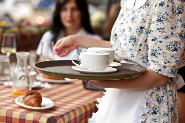 Cameriera che tiene vassoio con tazze di caffè in caffetteria