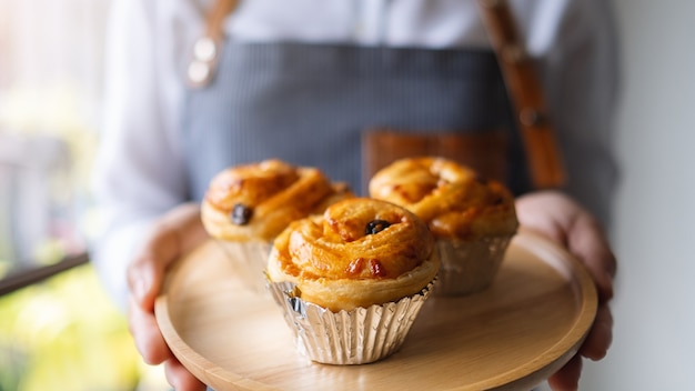 A waitress holding a wooden plate of raisin danish