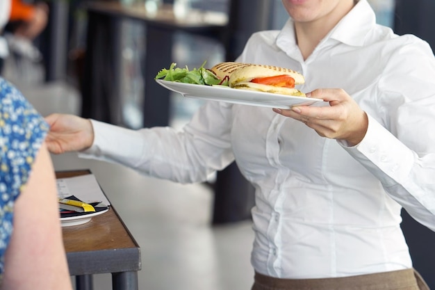 The waitress is carrying a plate of food to the client