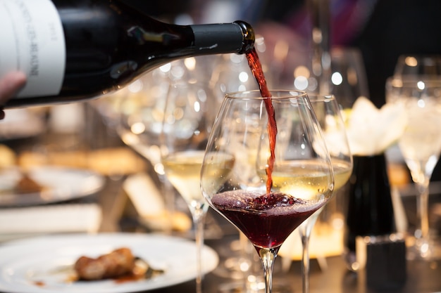 Photo waitress pour red wine in the glass on the table in restaurant