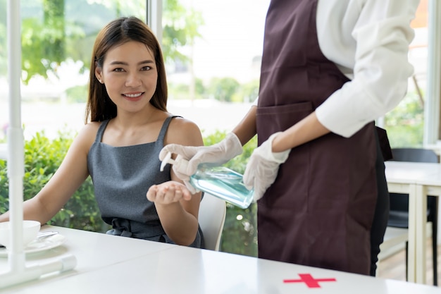 Waitress push hand sanitizer for customer.