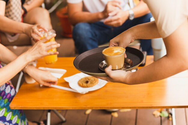 Waitress serving hot latte coffee to customer at cafe