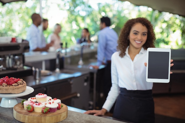 Cameriera che mostra tavoletta digitale al caffè all'aperto