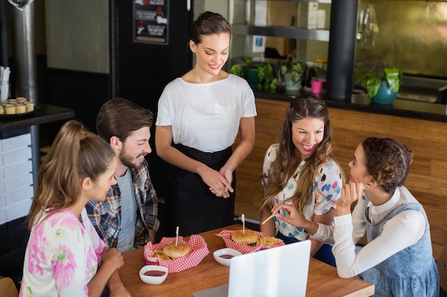 Waitress standing by customers in +restaurant