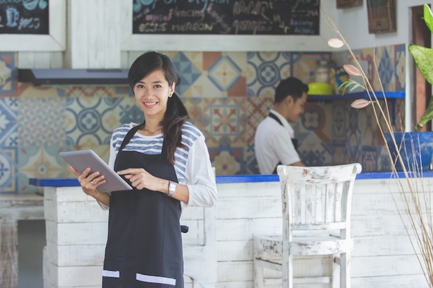 Waitress using digital tablet in cafe