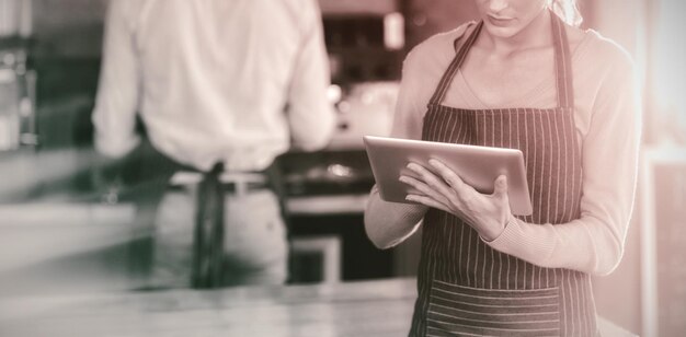 Waitress using digital tablet at counter