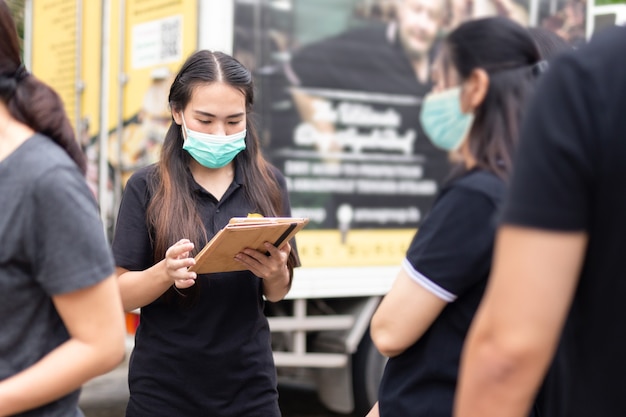 Waitress wearing protective mask while taking order on touchpad.