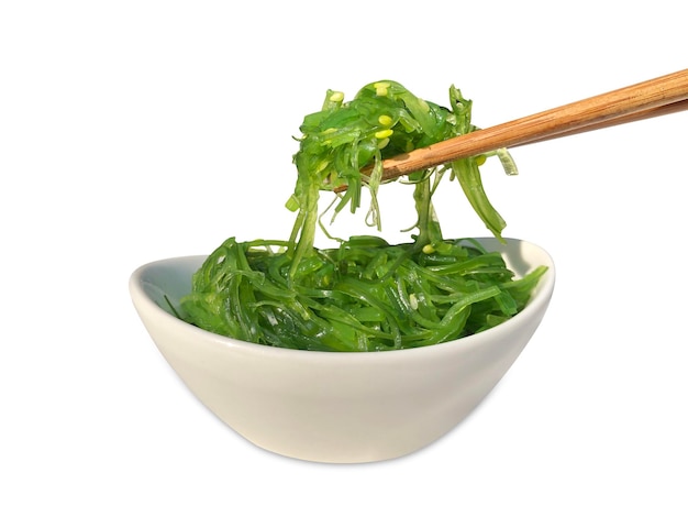 Wakame seaweed salad with chopsticks isolated on white background