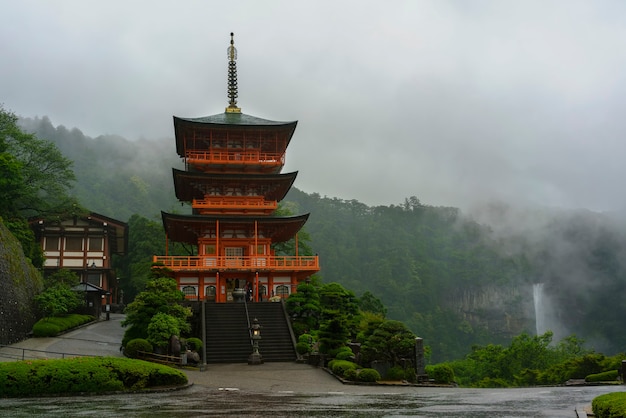 Wakayama , Japan - May 8 , 2018 : Three-story Sanjudo pagoda of Seiganto-ji temple with Nachi falls  in the rain , listed as a UNESCO World Heritage Site in Wakayama Prefecture