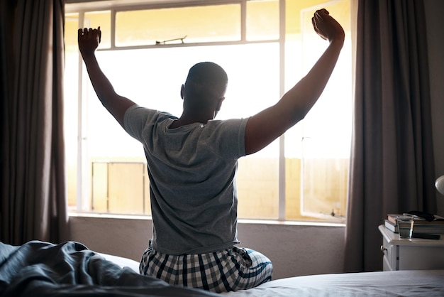 wake up stretching and black man in bedroom in morning for relaxing resting and sleeping apartment house and person with pillow blanket and comfortable for health peace and calm for nap