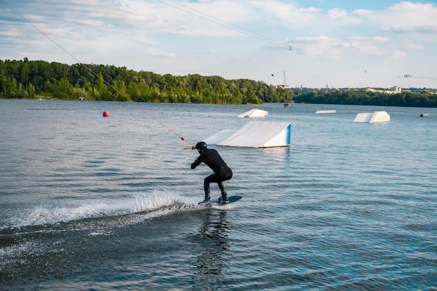 Wakeboarder die op het water aan boord glijdt en zich klaarmaakt om een hellingsprong uit te voeren