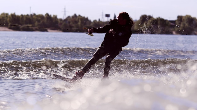 Wakeboarding-rijder geniet van het trainen van Surfer die trick maakt op wakeboard