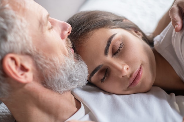 Waking up. A woman sleeping on her spouses sholuder in the morning