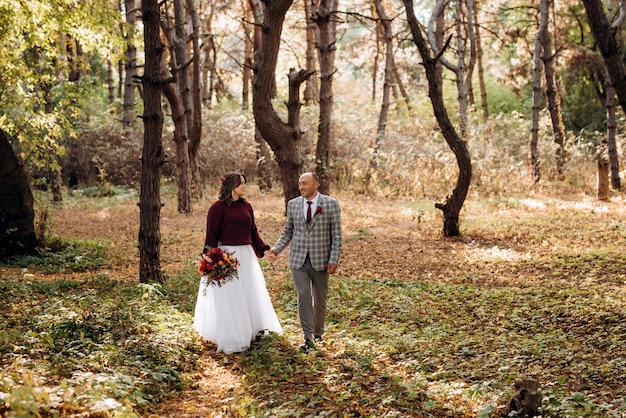 Walk of the bride and groom through the autumn forest in October