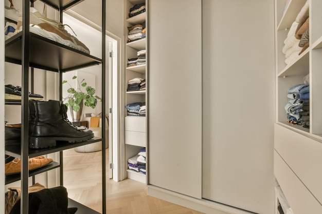 a walk in closet with lots of clothes and shoes hanging on the wall behind it is an open white door