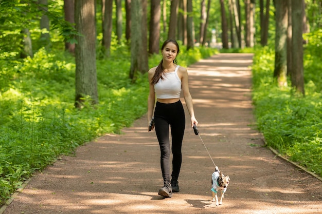 犬を散歩する女の子はひもにつないでペットと一緒に歩く