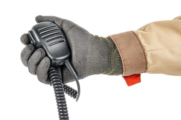 Walkie talkie handheld microphone with spiral connection cord in male hand in black protective glove and brown uniform on white