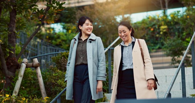 歩き歩きの会話とビジネス 都市の女性はコミュニケーションや結びつきのために話します 笑顔の議論とプロのアジアの女性の人々は話し合い,一緒に笑っています 町で通勤しています