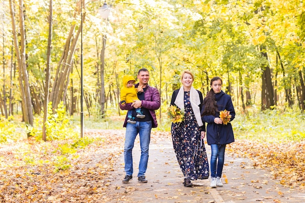 Гуляющая семья с двумя детьми в осеннем парке.