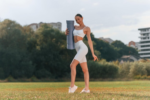 Walking on the field Young caucasian woman with slim body shape is in the fitness clothes outdoors