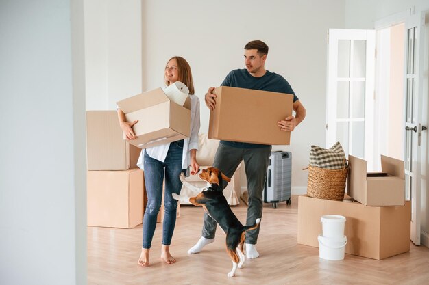 Photo walking forward with boxes young couple with dog are moving to new home