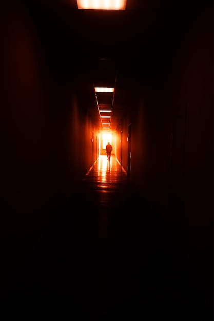劇的な日没の間にオフィスの廊下で歩く男