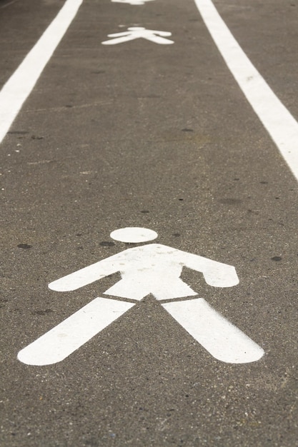 コンクリートの道に白く塗られた歩行者の歩行者用標識