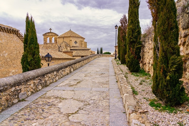 Walking path between cypress trees and medieval buildings Cuenca Spain