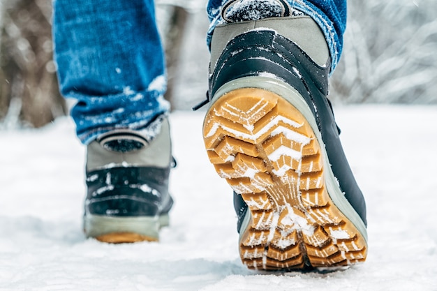 雪の中を歩きます。冬の靴のクローズアップ