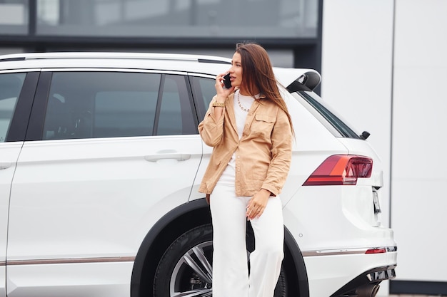 Прогулки рядом с машиной Модная красивая молодая женщина и ее современный автомобиль