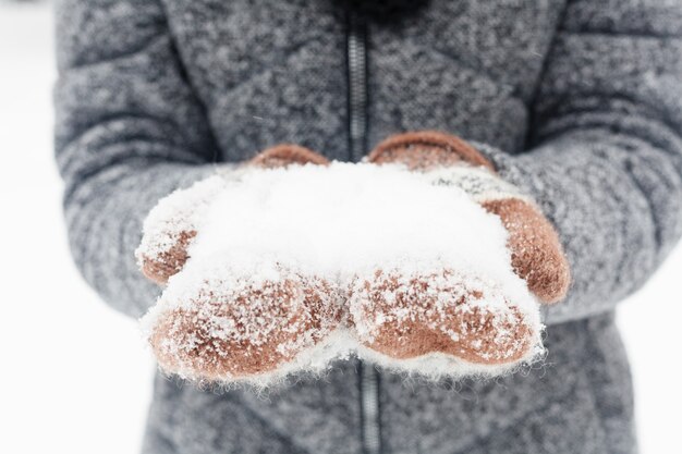 Walks, season and people concept - happy young woman holding snow in winter park