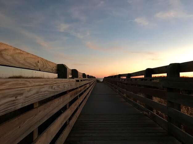 Walkway against sky during sunset