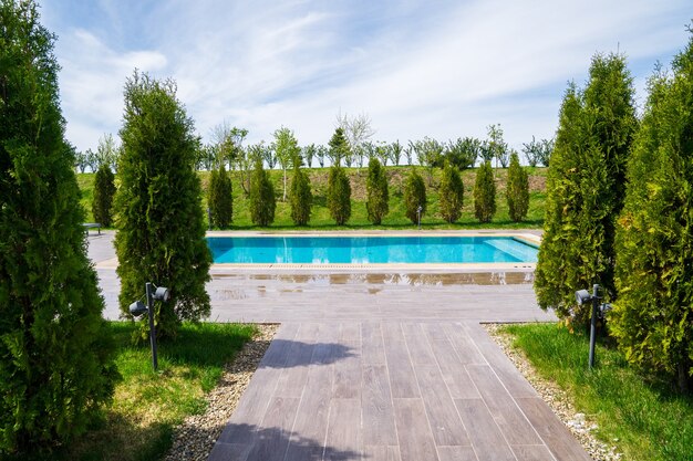 Una passerella rivestita di piastrelle alla piscina tra gli alberi. riposa in campagna. spa o country club