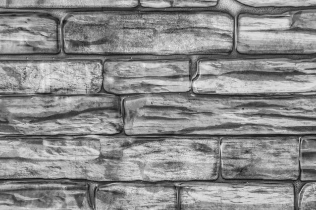 Wall of bricks of different shapes close-up black and white.