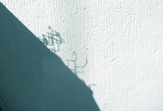 The wall of the building with the shadow of the roof and iron mesh