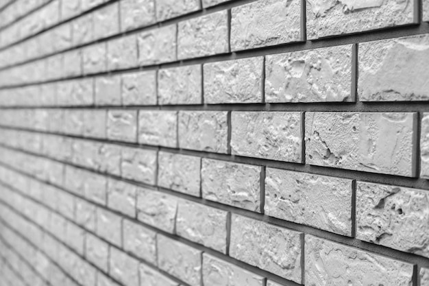 The wall of a country house, sheathed with white plastic facade panels in the form of bricks.
