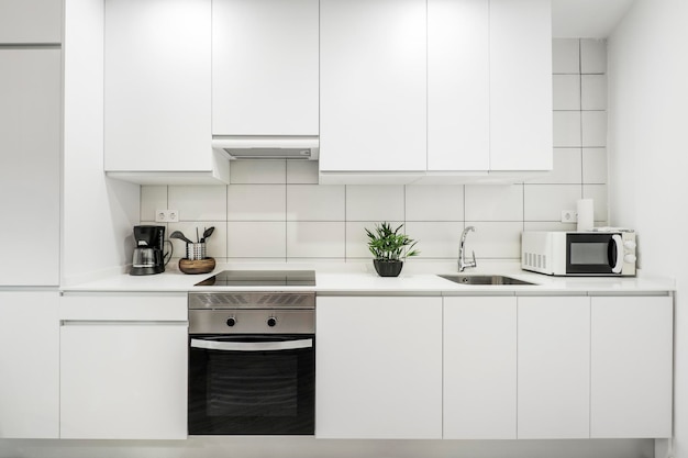 Photo wall covered with white kitchen furniture with white silestone countertop and rectangular tiles