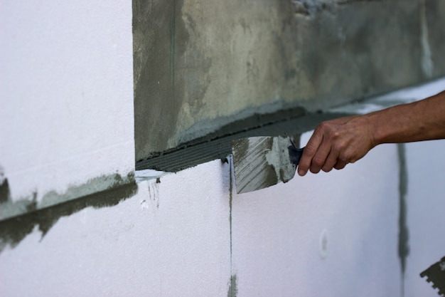 Wall insulation with polystyrene panels, glue application and installation.