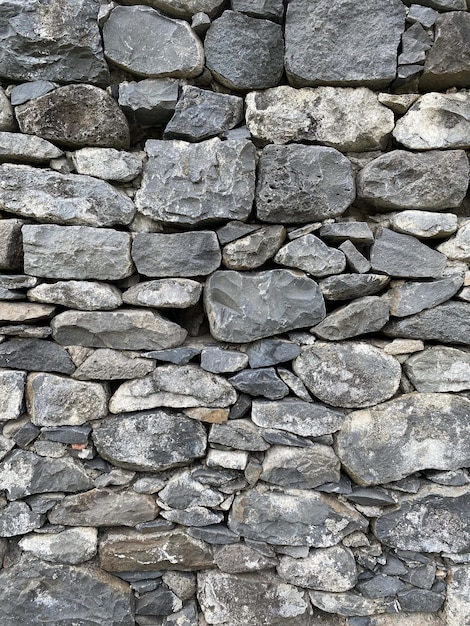 The wall is made of large and small gray stones side view texture