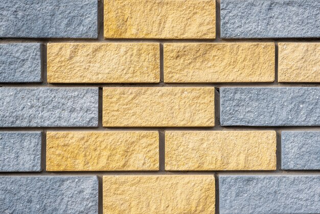 Wall of light grey and yellow colors stone blocks