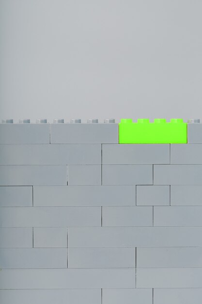 A wall made of children's construction kit parts with bright green bricks