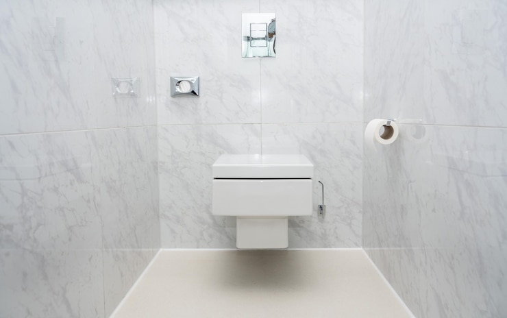 Photo プッシュボタン水洗付きの豪華なタイル張りのバスルームに壁に取り付けられたミニマリストトイレまたはトイレ