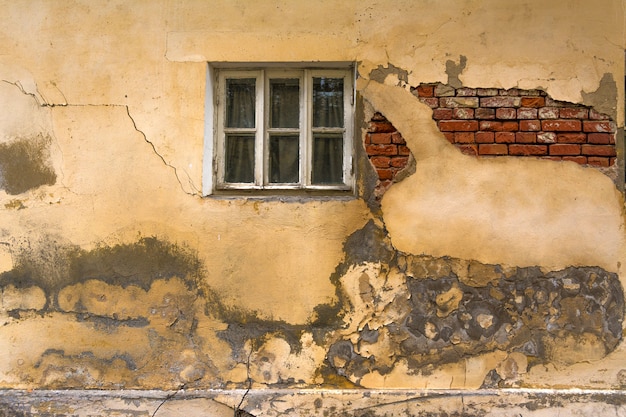 The wall of an old house with a window. The wall needs repair, Collapsed plaster and brickwork.