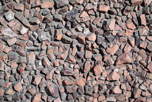 Wall of red granite stones background and texture