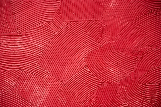 赤いペンキで覆われたパテの深い円形の塗りで壁のテクスチャ。