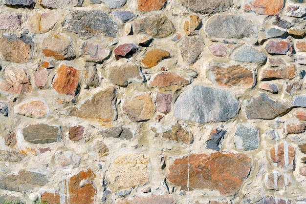 A wall of uneven stones vintage building stone background