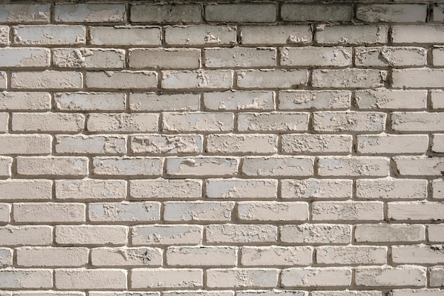 Wall of white brick with peeling off paint outdoors textured\
background